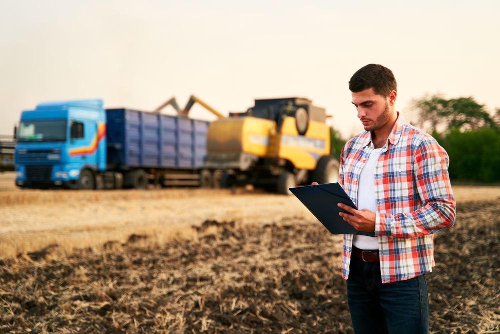 Farmer,Controls,Loading,Wheat,From,Harvester,To,Grain,Truck.,Driver